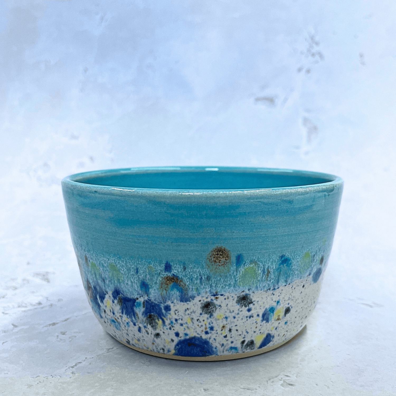 Ella Fletcher Designs UK Handmade Ceramic Small Bowl in Blue Shoreline design, round bowl with pale blue and multicolour speckles, side view