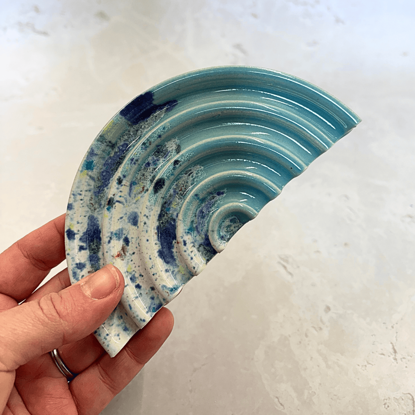 Ella Fletcher Designs Handmade Ceramics Soap Dish in Blue Shoreline design, semi-circle with grooved edges, half pale blue and half multi-coloured speckles