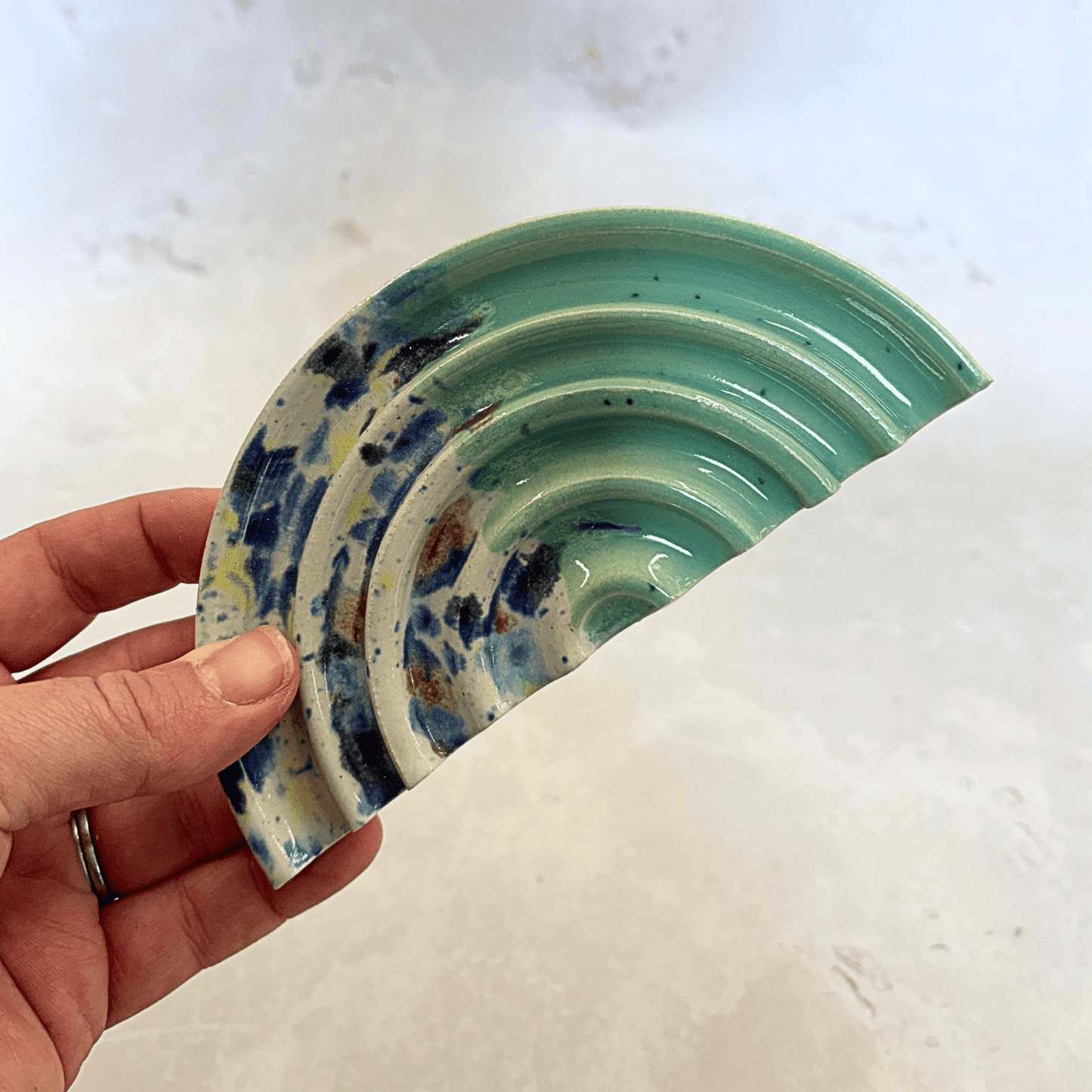 Ella Fletcher Designs Handmade Ceramics Soap Dish in Green Shoreline design, semi-circle with grooved edges, half pale green and half multi-coloured speckles