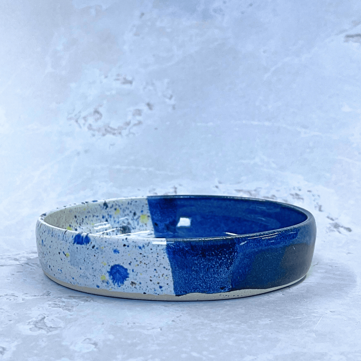 Ella Fletcher Designs Handmade Ceramic Trinket Dish in Navy Shoreline Design, small round dish with dark blue and multicolour speckles side view
