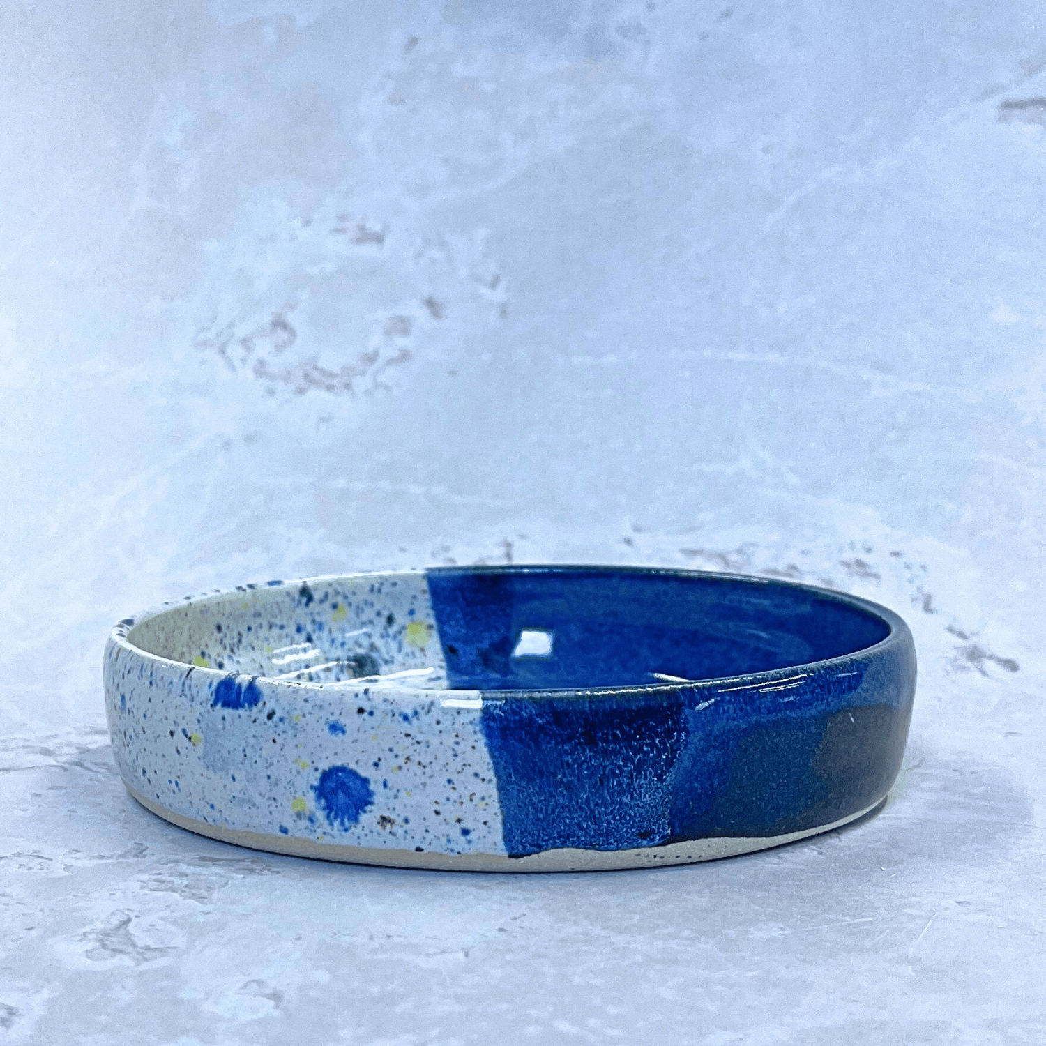 Ella Fletcher Designs Handmade Ceramic Trinket Dish in Navy Shoreline Design, small round dish with dark blue and multicolour speckles side view