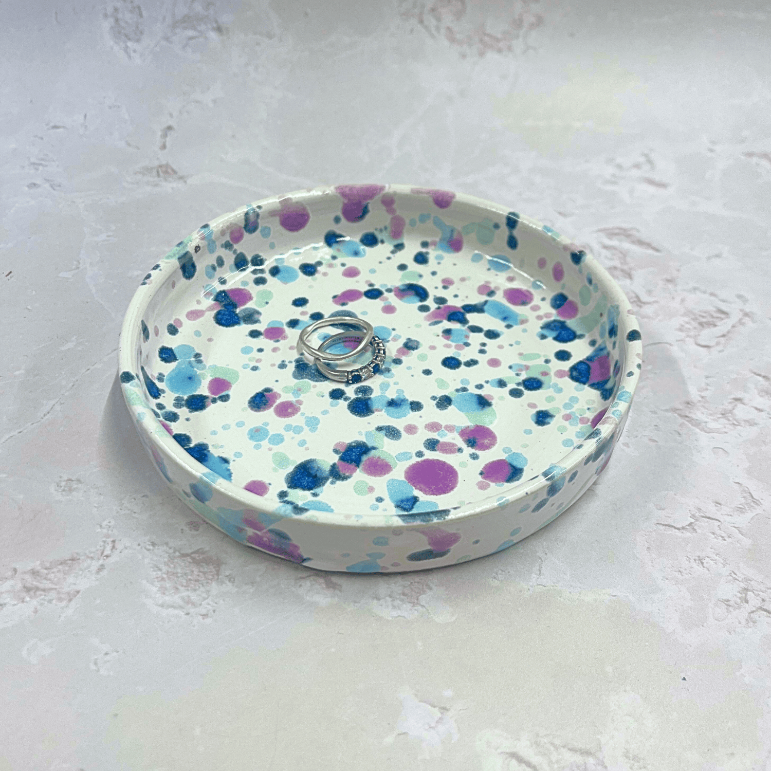 Ella Fletcher Designs Handmade Ceramic Trinket Dish in Sweetpea Design, white background with speckles of blues and pink to resemble sweet pea flowers, featured with rings