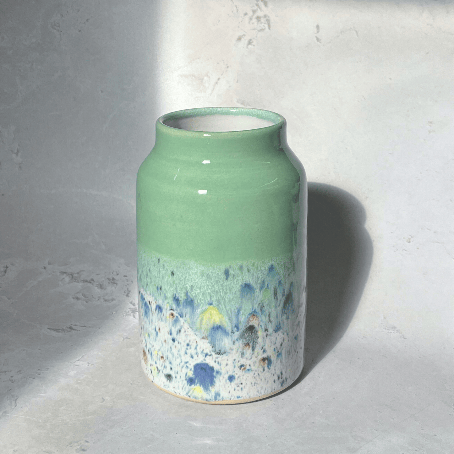 Ella Fletcher Designs Handmade Pottery Vase in Pale Green Shoreline Design - vase with solid green top and multi-coloured speckles at the bottom