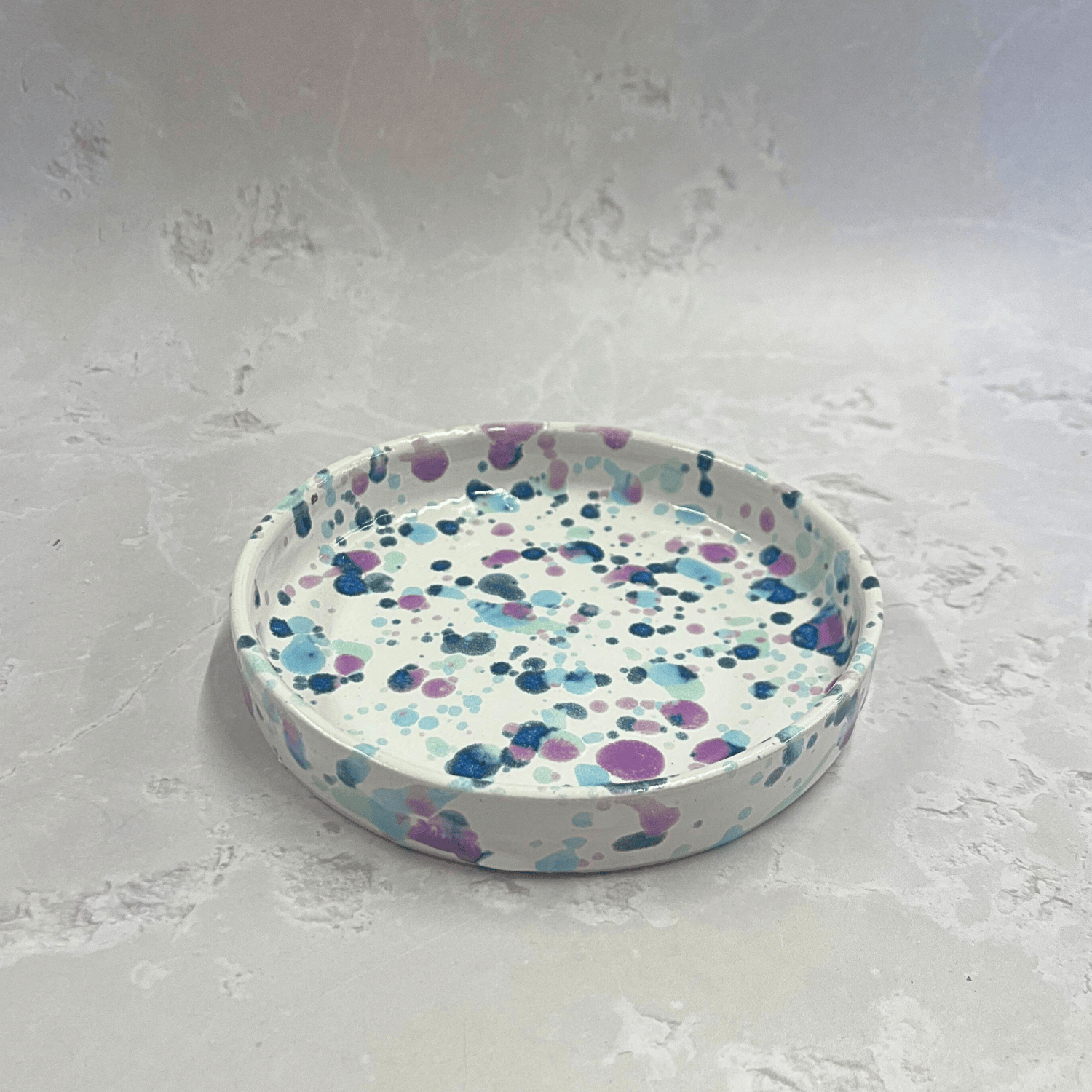 Ella Fletcher Designs Handmade Ceramic Trinket Dish in Sweetpea Design, white background of a small circular dish with speckles of blues and pink to resemble sweet pea flowers