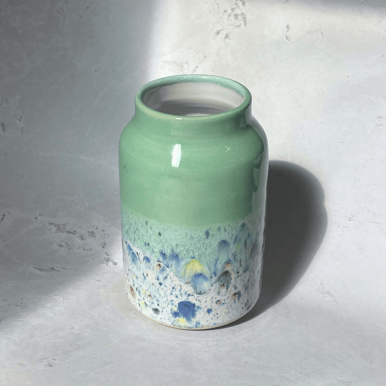 Ella Fletcher Designs Handmade Pottery Vase in Pale Green Shoreline Design - vase with solid green top and multi-coloured speckles at the bottom
