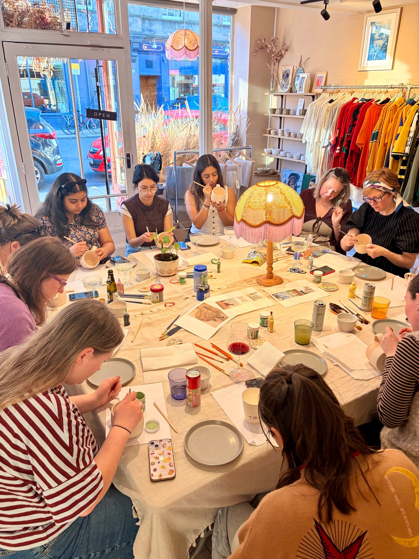 Group of people engaged in a craft activity at a table with various supplies.