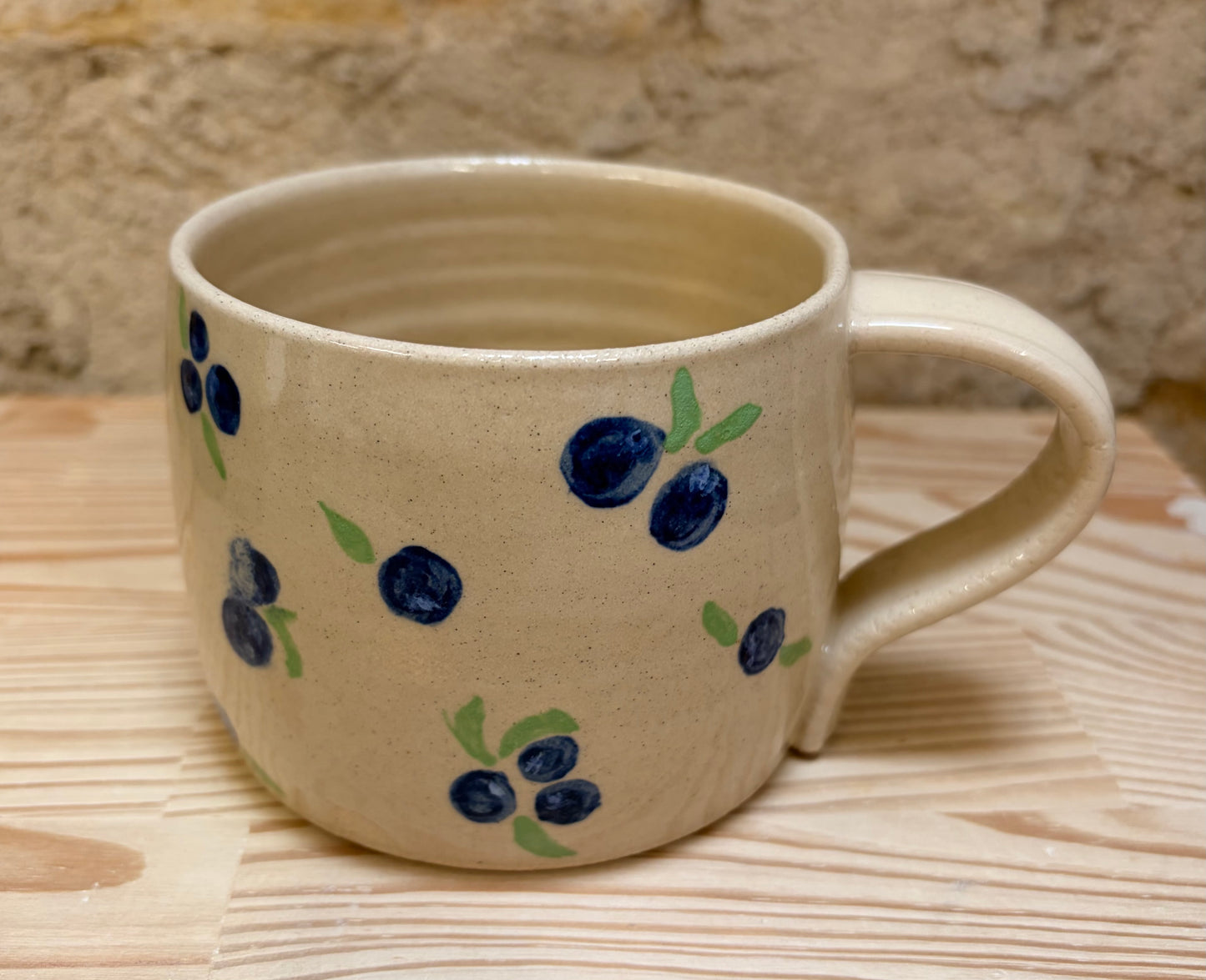 Ceramic mug with blueberry design on a wooden surface