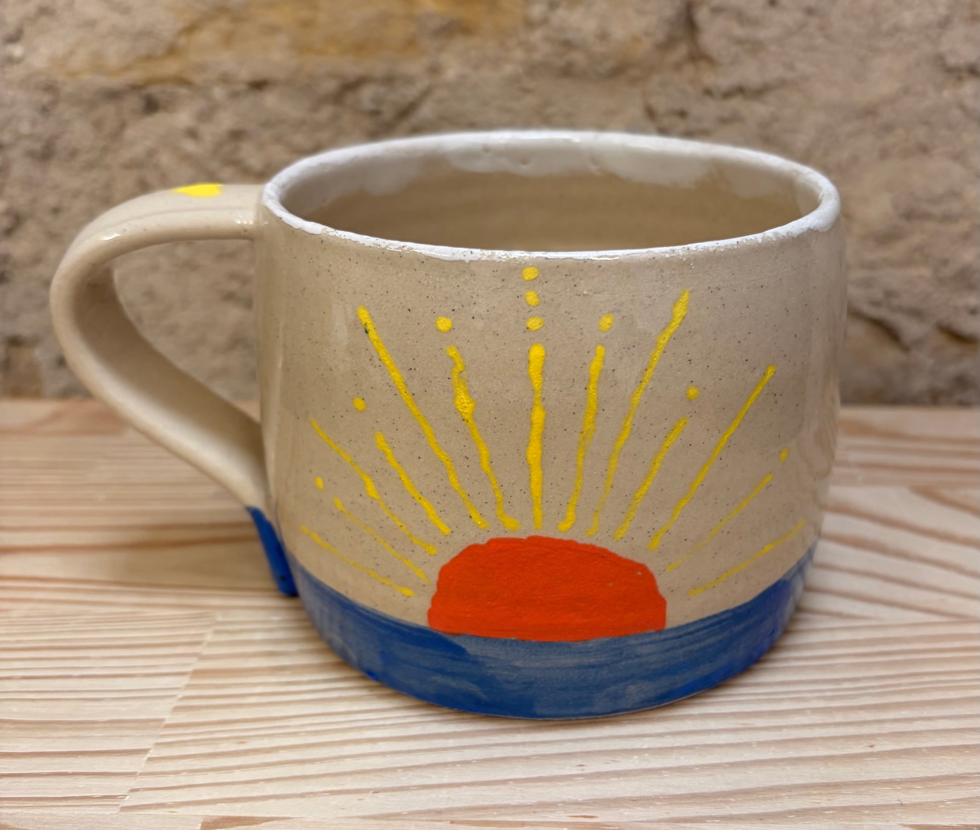 Ceramic mug with a sun design on a woven surface