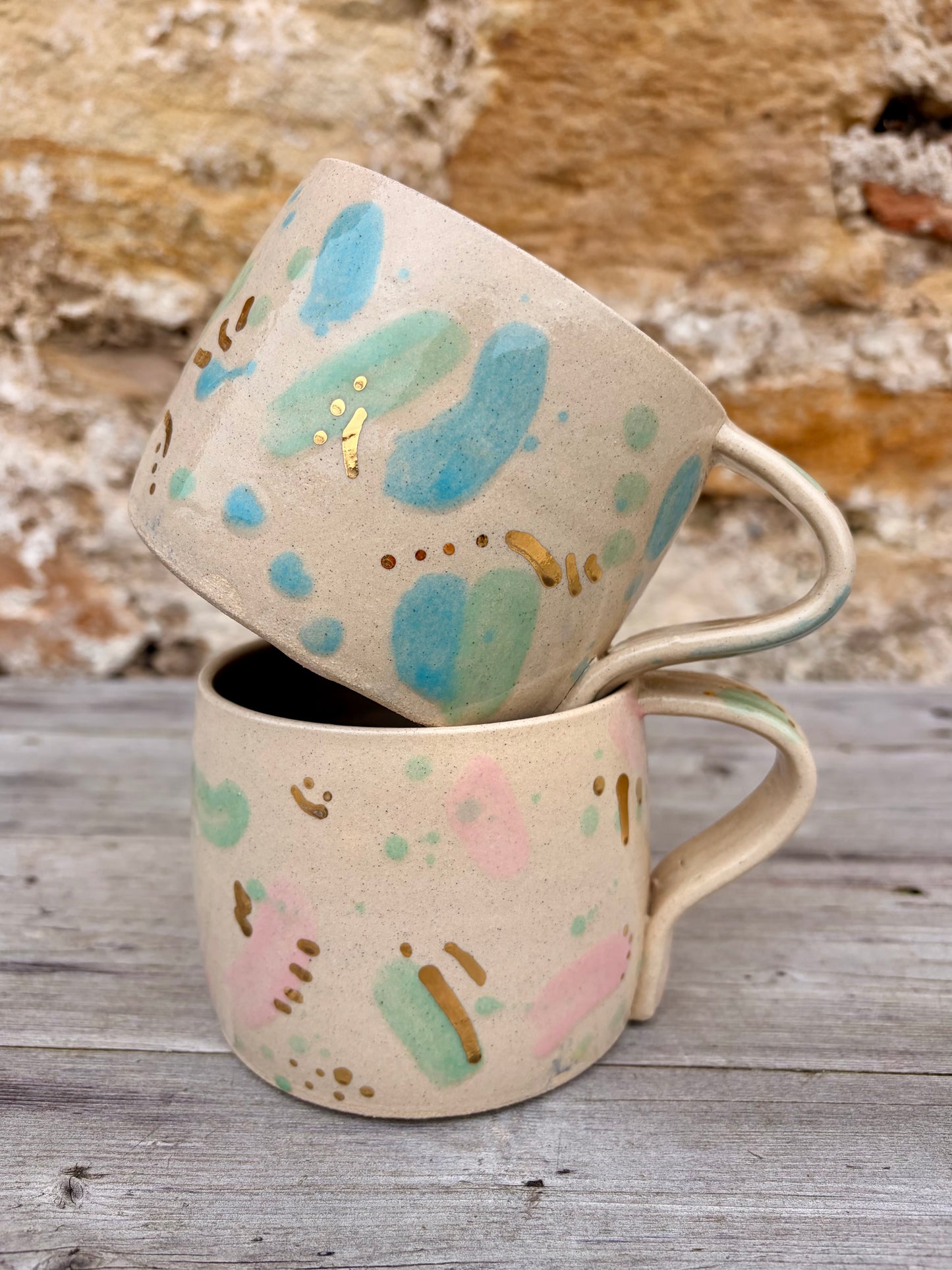 Two ceramic mugs with green, pink and blue sea glass design and gold lustre details