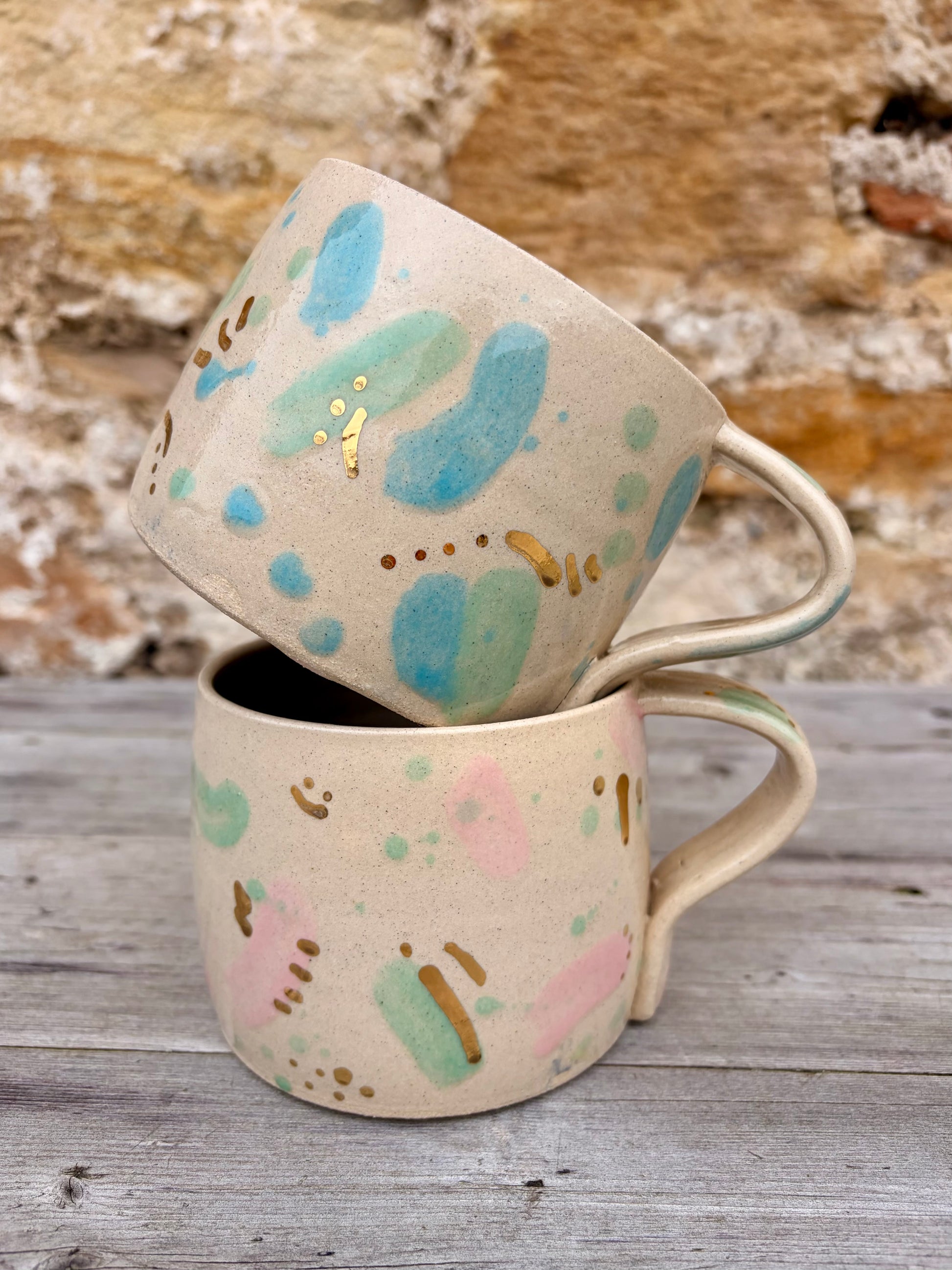 Two ceramic mugs with green, pink and blue sea glass design and gold lustre details